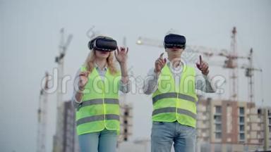 建筑工地的两名未来检查员在建筑物和建筑物的背景上使用虚拟现实眼镜。